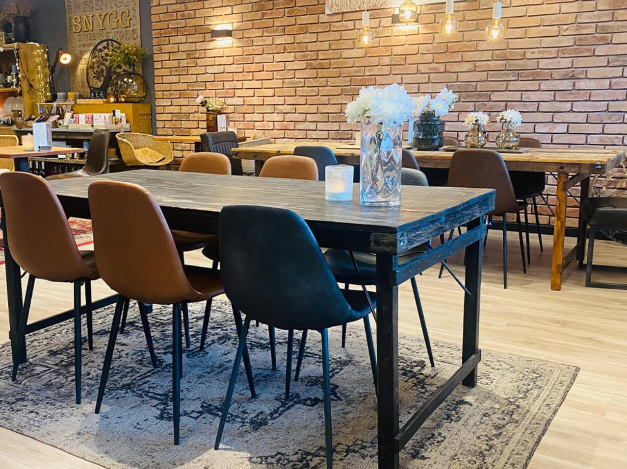 Cozy café interior design with raw brick walls, Trademark wooden tables, dining chairs, and decorative lamps, creating a warm and inviting atmosphere.